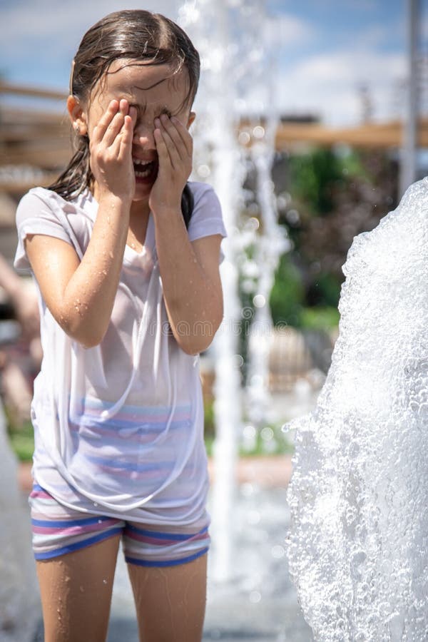 Una Niña Mojada Se Refresca En Una Fuente En Un Caluroso Día De Verano