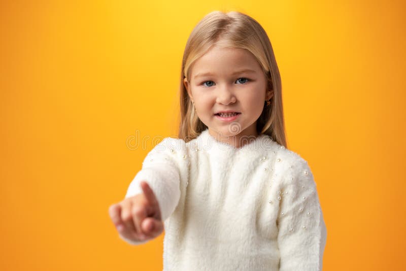 Little girl presses an imaginary button with her finger against yellow background. Little girl presses an imaginary button with her finger against yellow background