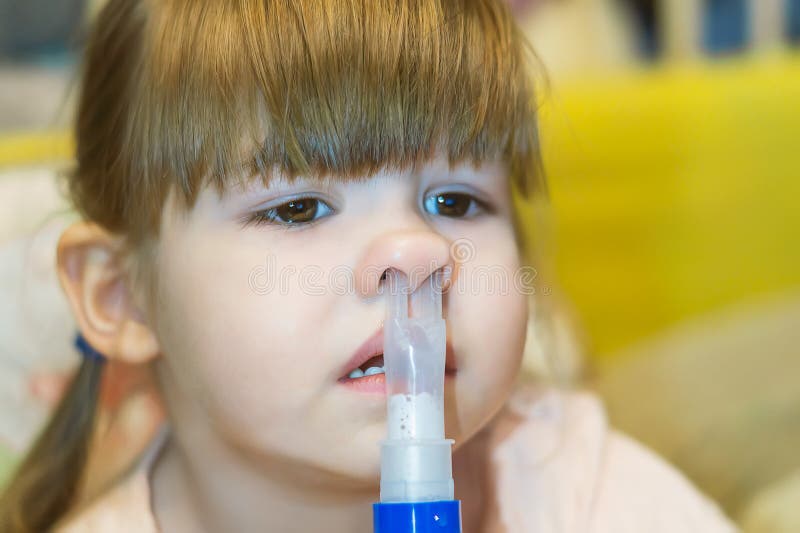 Una niña pequeña se somete a un procedimiento de inhalación para inhalar medicinas en su nariz mientras está en casa. tratamiento fotografía de archivo libre de regalías
