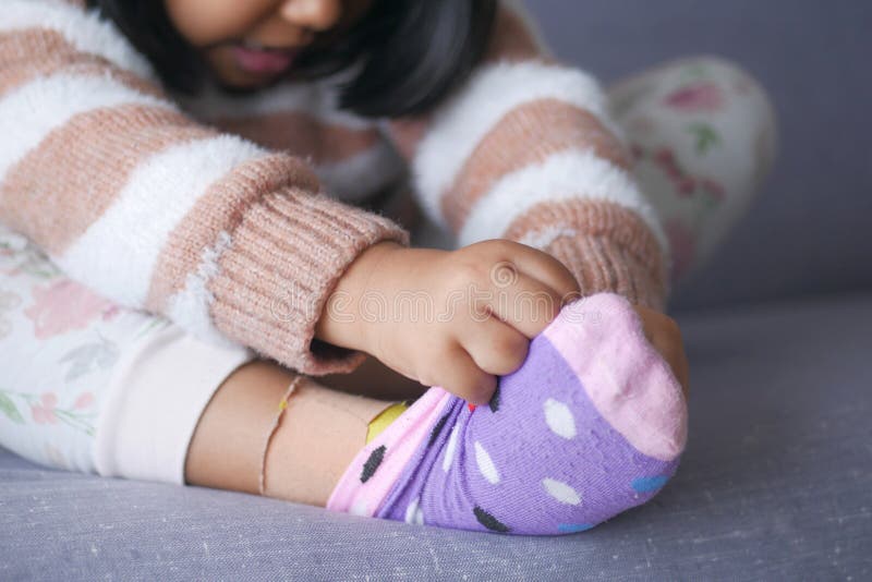 Una niña tratando de quitarse los calcetines