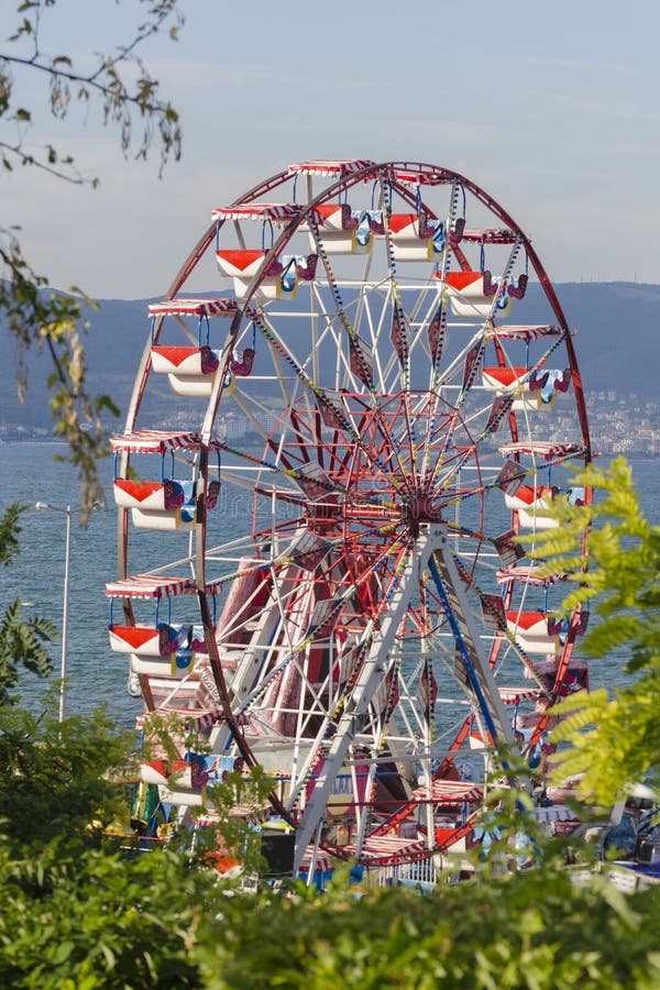 Una noria colorida en el parque de atracciones de la ciudad en el día de verano soleado sobre fondo del cielo azul Vista delanter fotos de archivo Una noria colorida en el parque de atracciones de la ciudad en el día de verano soleado sobre fondo del cielo azul Vista delanter fotos de archivo