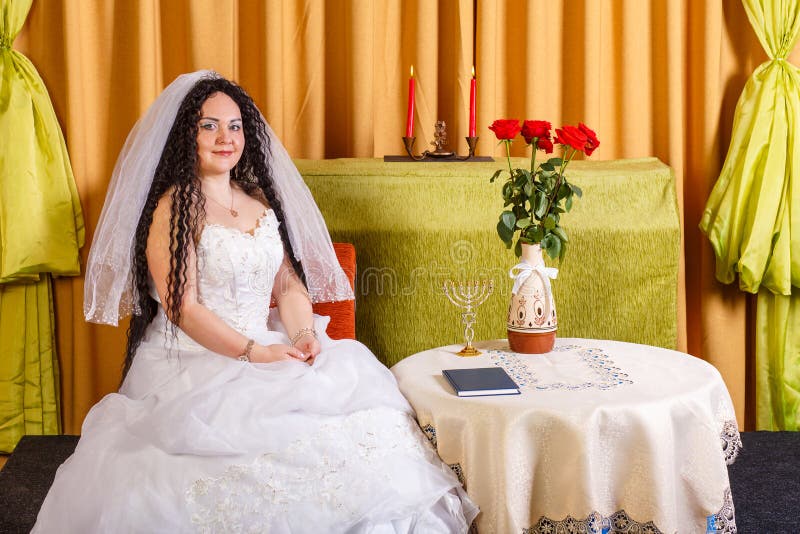 Una Novia Judía Con Un Vestido De Novia Blanco Con Velo Se Sienta En Una Mesa Con Flores Antes De La Ceremonia De La Chuppah. Foto de archivo - Imagen de impresionante, Una Novia Judía Con Un Vestido De Novia Blanco Con Velo Se Sienta En Una Mesa Con Flores Antes De La Ceremonia De La Chuppah. Foto de archivo - Imagen de impresionante,
