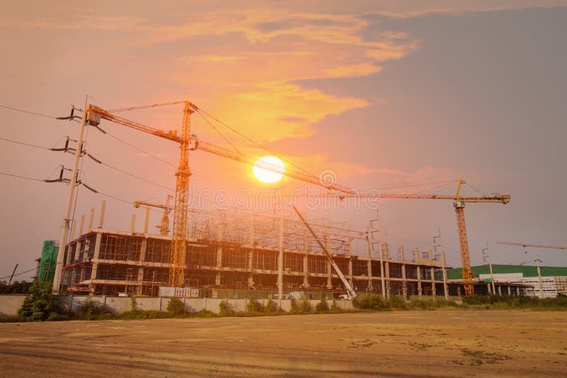 A construction site including several cranes working on a building, Boom crane on the construction of a high-rise and scaffolding in the building,with blue sky background, structure, industry, development, architecture, housing, built, concrete, sunset, estate, frame, occupation, engineering, equipment, teamwork, people, profession, group, property, helmet, manual, urban, workplace, progress, cement, real, installation, skyscraper, project, technology, activity, worker, laborer, industrial, business, flare. A construction site including several cranes working on a building, Boom crane on the construction of a high-rise and scaffolding in the building,with blue sky background, structure, industry, development, architecture, housing, built, concrete, sunset, estate, frame, occupation, engineering, equipment, teamwork, people, profession, group, property, helmet, manual, urban, workplace, progress, cement, real, installation, skyscraper, project, technology, activity, worker, laborer, industrial, business, flare