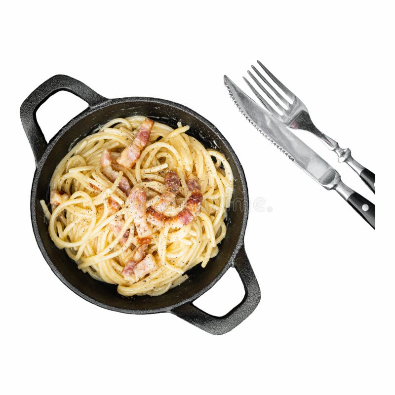 Una olla de hierro fundido con pasta recubierta de bacon crujiente se sienta sobre un fondo blanco. la cubertería de plata se encu. cubertería de plata colocada al lado de la olla para una deliciosa comida.