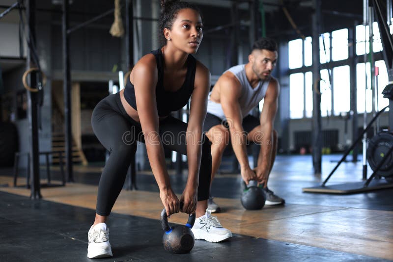 Una pareja apropiada y muscular se concentró en levantar un timbre durante una clase de ejercicio en un gimnasio