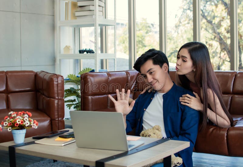 Una pareja encantadora asiático está utilizando la webcam en un ordenador portátil para charlar con sus primos