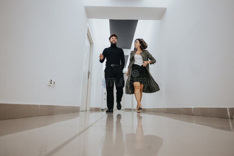 Energetic male and female business colleagues stride with purpose in a bright office corridor, conveying confidence and professionalism. Energetic male and female business colleagues stride with purpose in a bright office corridor, conveying confidence and professionalism.