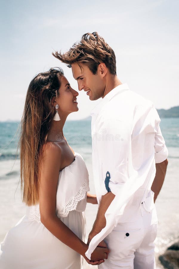 Foto de Pareja de jovenes en la playa vestidos de blanco un