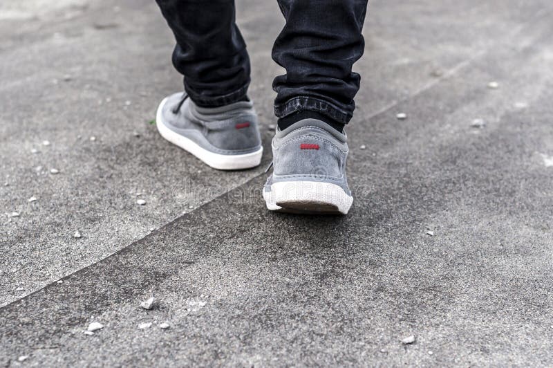 Una parte más inferior de las piernas masculinas en zapatillas de deporte grises fotos de archivo libres de regalías Una parte más inferior de las piernas masculinas en zapatillas de deporte grises fotos de archivo libres de regalías