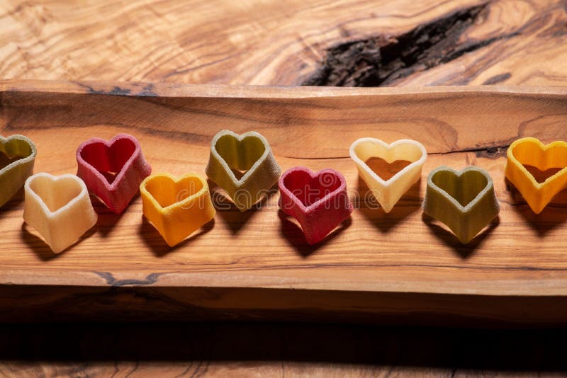 Una pasta in forma di cuore di 5 sapori del semolato di grano duro con le verdure sistemate sul piatto di legno verde oliva lungo fotografia stock libera da diritti Una pasta in forma di cuore di 5 sapori del semolato di grano duro con le verdure sistemate sul piatto di legno verde oliva lungo fotografia stock libera da diritti