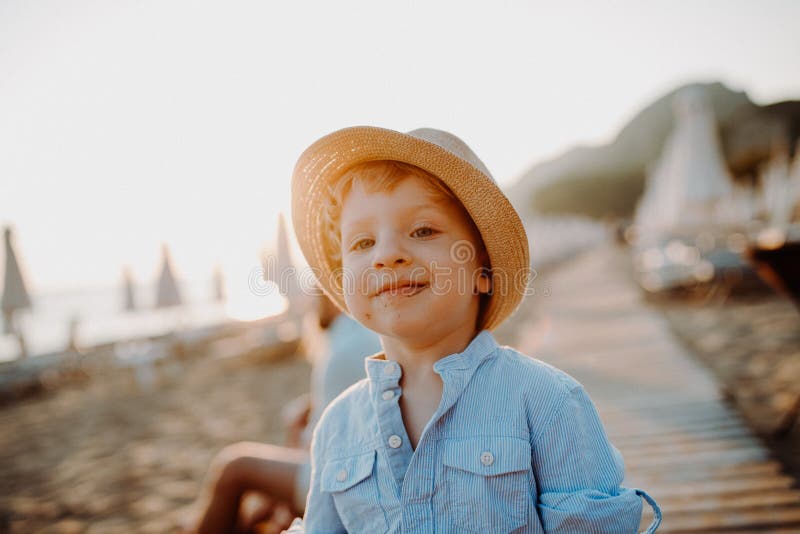 Una pequeña situación del niño pequeño en la playa el vacaciones de verano en la puesta del sol imagen de archivo libre de regalías Una pequeña situación del niño pequeño en la playa el vacaciones de verano en la puesta del sol imagen de archivo libre de regalías