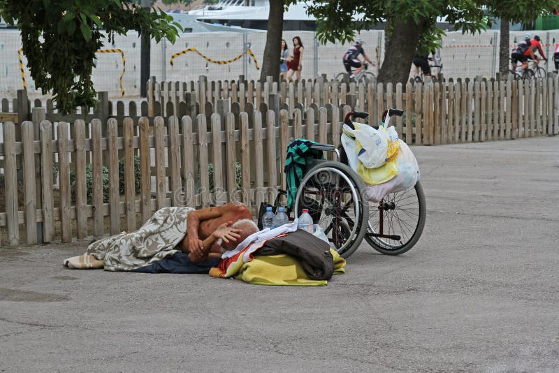 Una persona discapacitada sin hogar con una silla de ruedas que duerme en el asfalto en Barcelona imagenes de archivo Una persona discapacitada sin hogar con una silla de ruedas que duerme en el asfalto en Barcelona imagenes de archivo