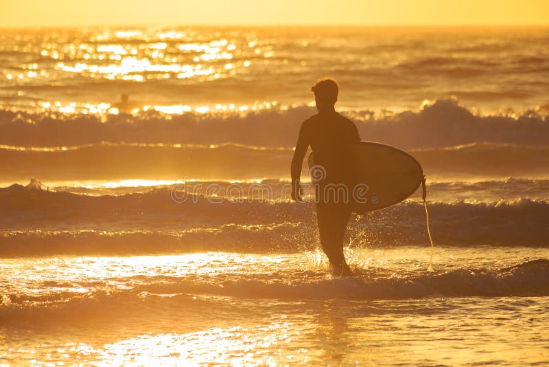 Una persona que practica surf que dirige hacia fuera en ondas de oro imagen de archivo Una persona que practica surf que dirige hacia fuera en ondas de oro imagen de archivo