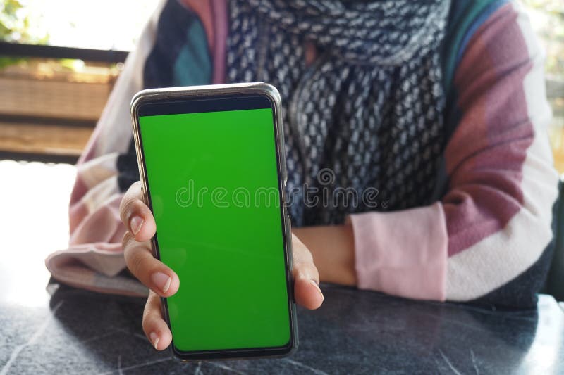 Una persona que usa un smartphone con pantalla verde para mostrar la tecnología moderna y la interacción digital fotos de archivo