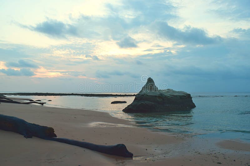 Una piedra grande en aguas de mar tranquilo en Sandy Beach prístino con colores en el cielo nublado de la mañana - Sitapur, Neil