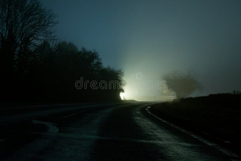 Una piega su una strada di campagna, con una luce luminosa all'orizzonte In una notte di inverni misteriosi immagine stock libera da diritti