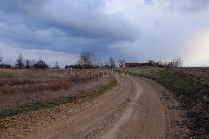 Una piegatura su una strada di campagna in un campo serale. paesaggio crepuscolo. cielo nuvoloso fotografia stock