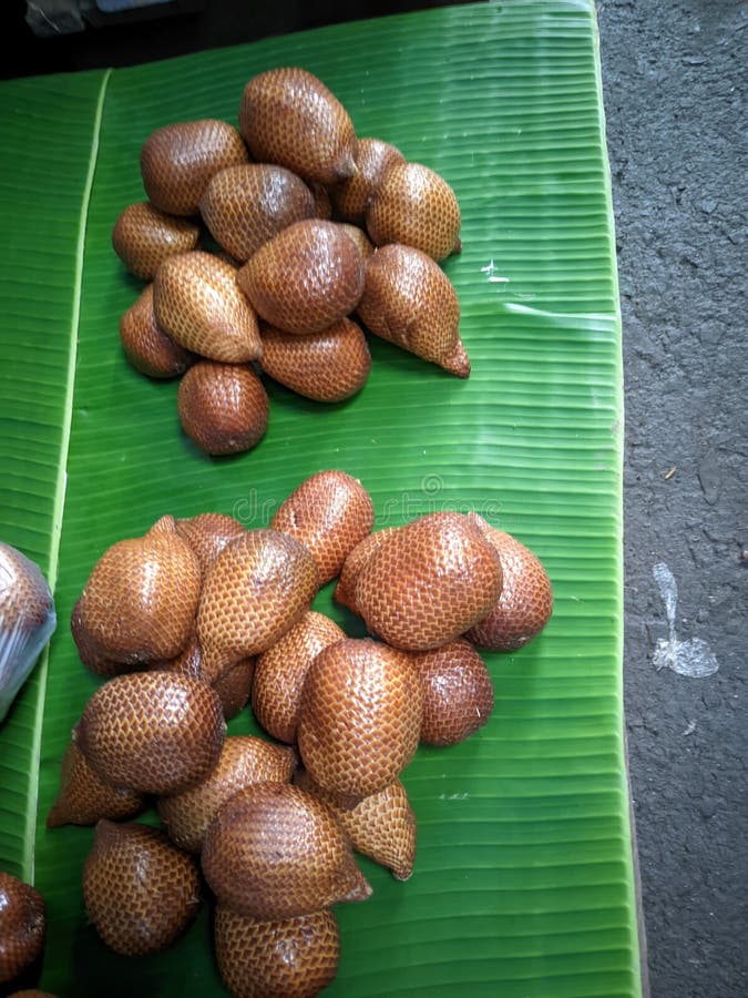 A pile of snake fruit on top of green leaves is a type of palm tree, the fruit looks snake. A pile of snake fruit on top of green leaves is a type of palm tree, the fruit looks snake