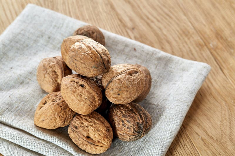 Una pila di gusci duri delle noci accatastate insieme sulla tovaglia grigio chiaro del cotone del tessuto, fuoco selettivo immagini stock Una pila di gusci duri delle noci accatastate insieme sulla tovaglia grigio chiaro del cotone del tessuto, fuoco selettivo immagini stock