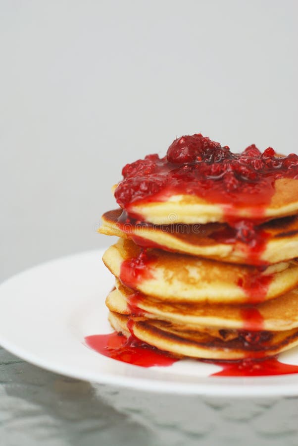 Una pila di pancake con l'inceppamento di fragola isolato sul piatto bianco e sul fondo grigio fotografie stock Una pila di pancake con l'inceppamento di fragola isolato sul piatto bianco e sul fondo grigio fotografie stock