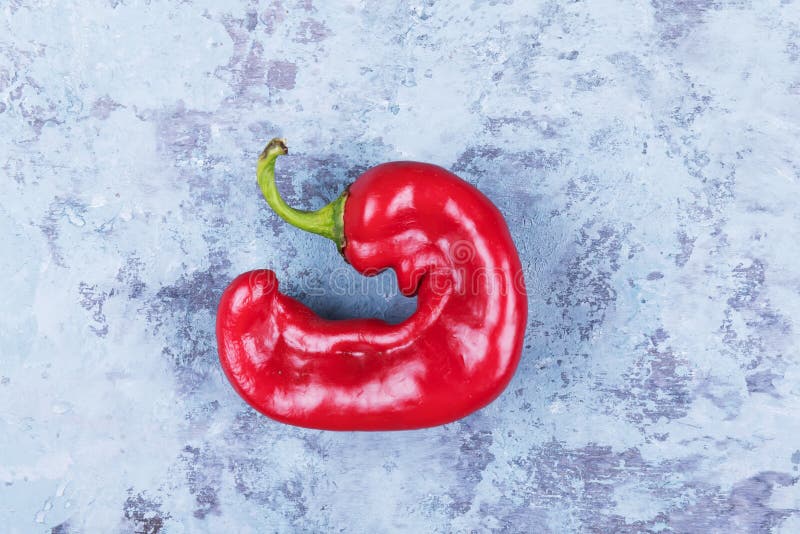 Una pimienta roja trendy y fea sobre un fondo de grano azul, estilo minimalista, concepto de cocina creativa foto de archivo Una pimienta roja trendy y fea sobre un fondo de grano azul, estilo minimalista, concepto de cocina creativa foto de archivo