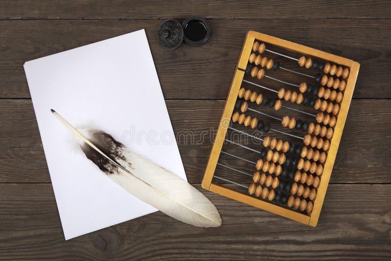 Una pluma del ganso miente en una pila de hojas de papel blancas Las viejas cuentas y un tintero retro están situados de lado a l fotografía de archivo libre de regalías Una pluma del ganso miente en una pila de hojas de papel blancas Las viejas cuentas y un tintero retro están situados de lado a l fotografía de archivo libre de regalías