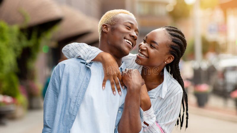 Una ragazza afro-americana felice abbraccia un uomo con sacchi di colore vicino ai negozi immagini stock libere da diritti