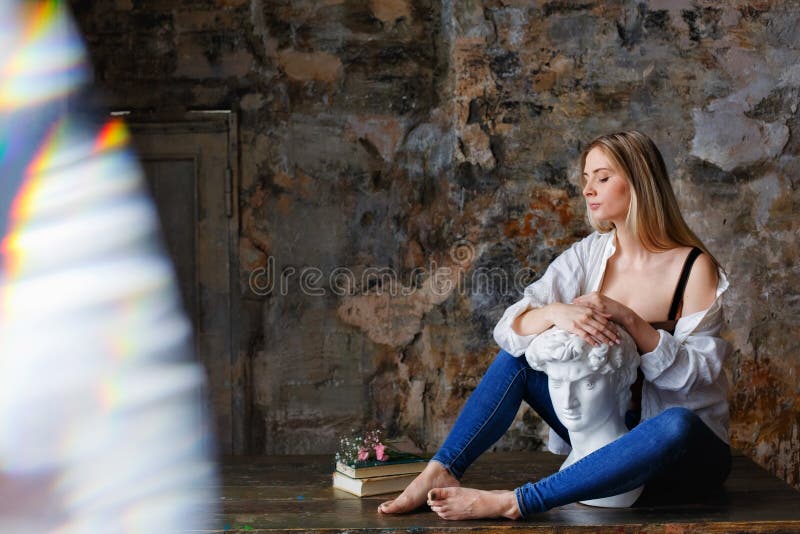 A blonde girl embraces a bust of David in the workshop. A blonde girl embraces a bust of David in the workshop.