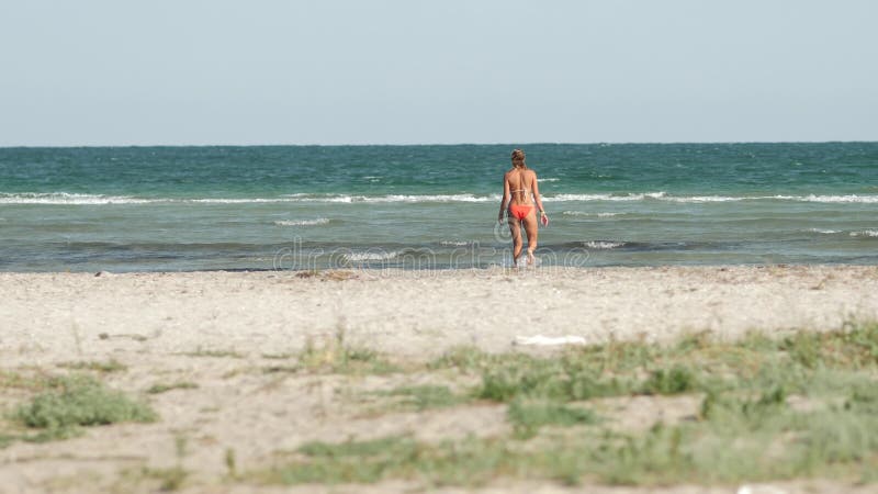 Una ragazza cammina lungo la costa verso il mare da sola