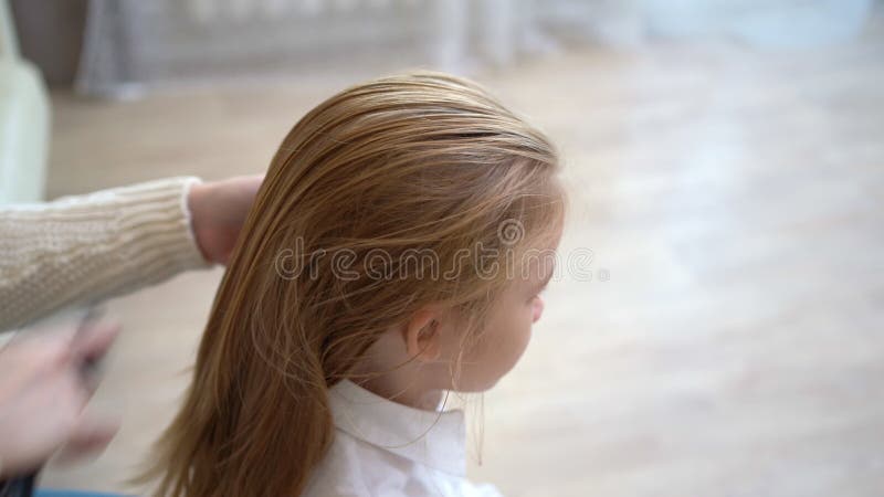 Una ragazza di una scuola dolce seduta mentre la madre pettina i capelli primi aumenti a scuola video d archivio