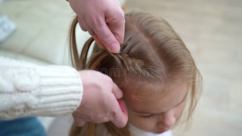 Una ragazza di una scuola dolce seduta mentre la madre tira i capelli. primi aumenti a scuola. archivi video