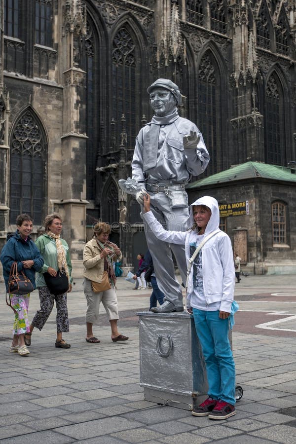 Una ragazza fa la sua prendere fotografia con un esecutore della via della statua dipinto in argento a Vienna in Austria fotografia stock Una ragazza fa la sua prendere fotografia con un esecutore della via della statua dipinto in argento a Vienna in Austria fotografia stock