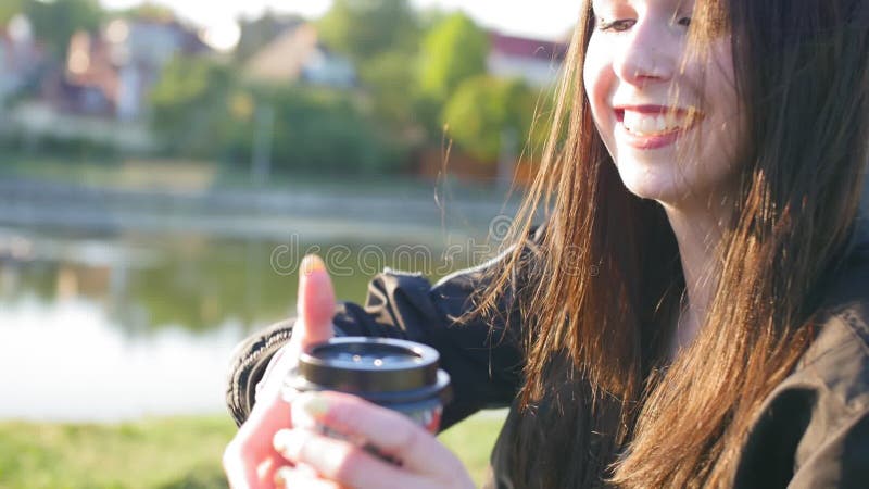 Una ragazza felice con capelli lunghi neri e labbra rosse beve caffè Nello stagno di fondo Chiudi ripresa