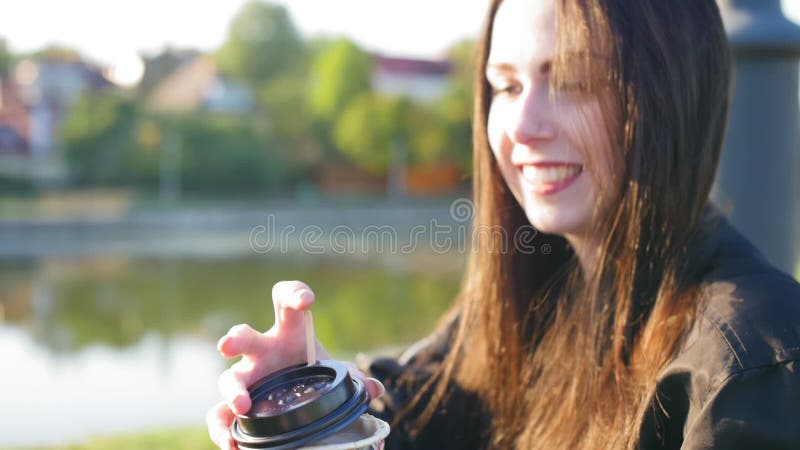 Una ragazza felice con capelli lunghi neri e labbra rosse beve caffè Nello stagno di fondo Chiudi ripresa