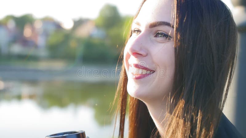Una ragazza felice con capelli lunghi neri e labbra rosse beve caffè Nello stagno di fondo Chiudi ripresa
