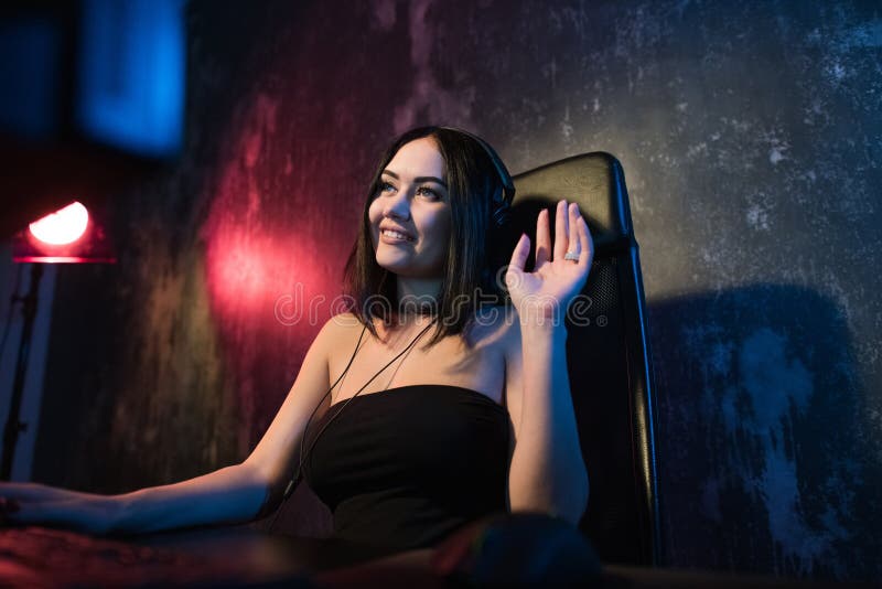 Una ragazza femminile sveglia del gamer si siede in una stanza accogliente dietro un computer e gioca Video scorrente in tensione immagine stock libera da diritti Una ragazza femminile sveglia del gamer si siede in una stanza accogliente dietro un computer e gioca Video scorrente in tensione immagine stock libera da diritti