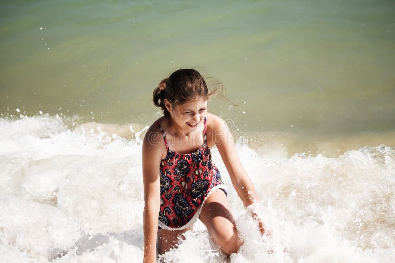 Una ragazza graziosa che gioca nelle onde sulla spiaggia, fuoco molle, concetto della spiaggia fotografia stock libera da diritti Una ragazza graziosa che gioca nelle onde sulla spiaggia, fuoco molle, concetto della spiaggia fotografia stock libera da diritti