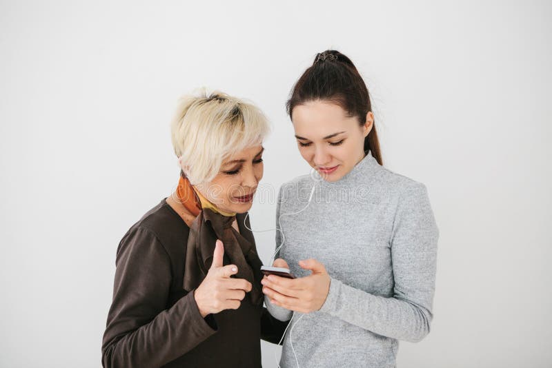 Una ragazza spiega ad una donna anziana come utilizzare un cellulare o mostra una certa applicazione o insegna a come usare la a fotografia stock Una ragazza spiega ad una donna anziana come utilizzare un cellulare o mostra una certa applicazione o insegna a come usare la a fotografia stock