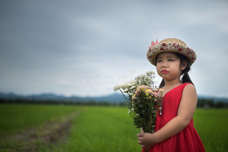 Una ragazza sveglia che tratta i fiori con emozione triste del fronte fotografia stock Una ragazza sveglia che tratta i fiori con emozione triste del fronte fotografia stock