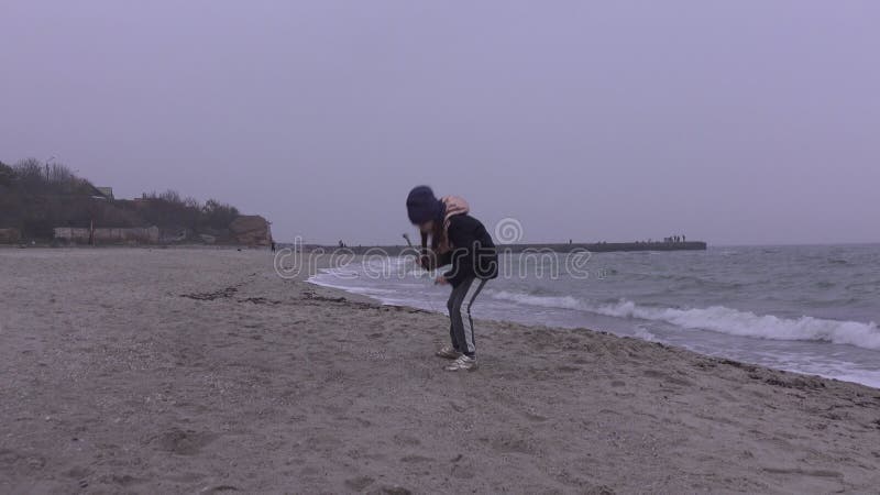 Una ragazzina passeggia sulla spiaggia in autunno