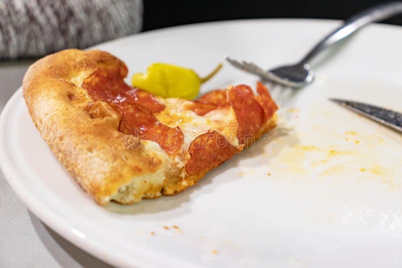 Una rebanada de pizza de pepperoni en plato blanco con folclore y cuchillo en una mesa del restaurante italiano fotografía de archivo Una rebanada de pizza de pepperoni en plato blanco con folclore y cuchillo en una mesa del restaurante italiano fotografía de archivo