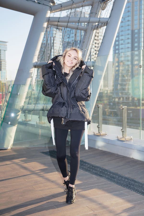 Una rubia agradable vestida con una abrigada chaqueta y pantalones foto de archivo libre de regalías