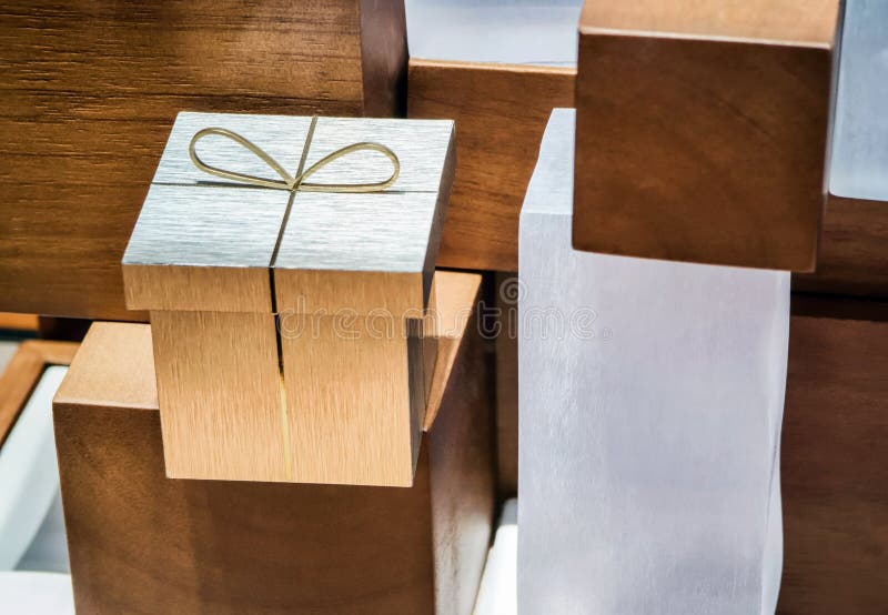 Una scatola regalo in legno decorativa raffigurata tra blocchi di legno scultorei in una mostra d'arte immagini stock