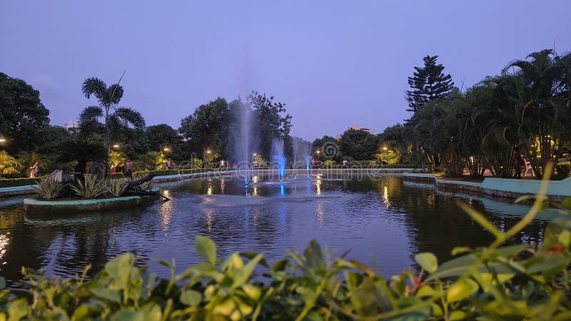Una serata tranquilla in una fontana di Urban Park con luci colorate fotografia stock