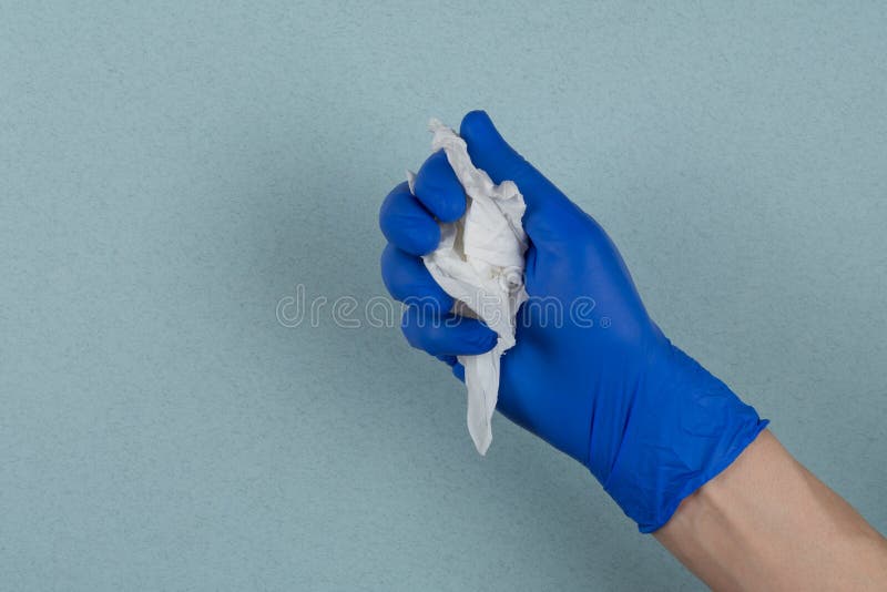 Una servilleta usada en ruinas en los médicos engullió la mano en un fondo azul foto de archivo libre de regalías