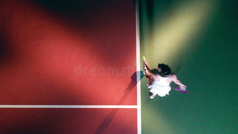 Una señora está sirviendo una pelota de tenis en una vista superior