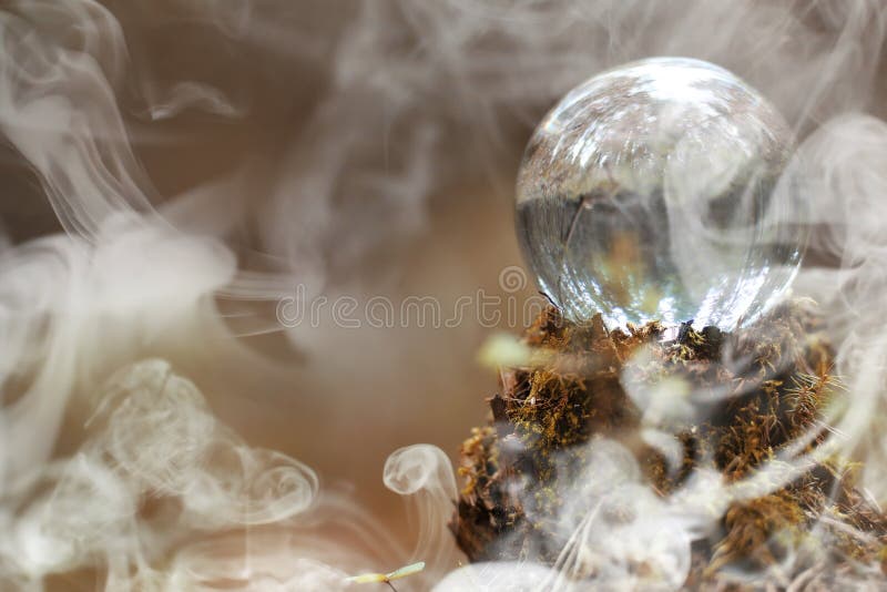 A crystal ball in the smoke. A magical accessory in the woods on the stump. Ritual ball of witches and sorcerers on an old rotten stump.r. A crystal ball in the smoke. A magical accessory in the woods on the stump. Ritual ball of witches and sorcerers on an old rotten stump.r