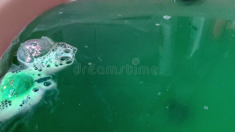 Una sfera di sale da bagno si dissolve in acqua accanto a una sfera di olio essenziale per una migliore doratura della bomba a bag
