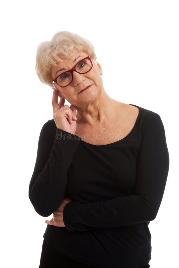 Una signora anziana in occhiali tocca il suo fronte. immagini stock libere da diritti