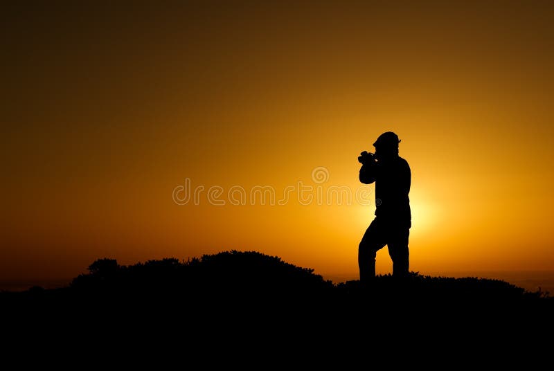 A silhouette of cameraman with golden light in the morning. A silhouette of cameraman with golden light in the morning.